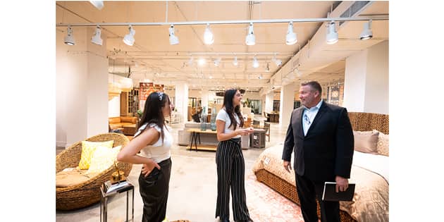 Pictured L to R are interior design majors Juliana Maniscalco, Anastasia Avlonitis and a potential client. Part of their job is to interact with customers and direct them to the different designs at Primitive Collections.